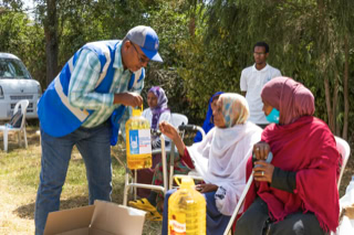 Smiling Ethiopian women receiving a food parcel from an Islamic Relief Ethiopia aid worker.
